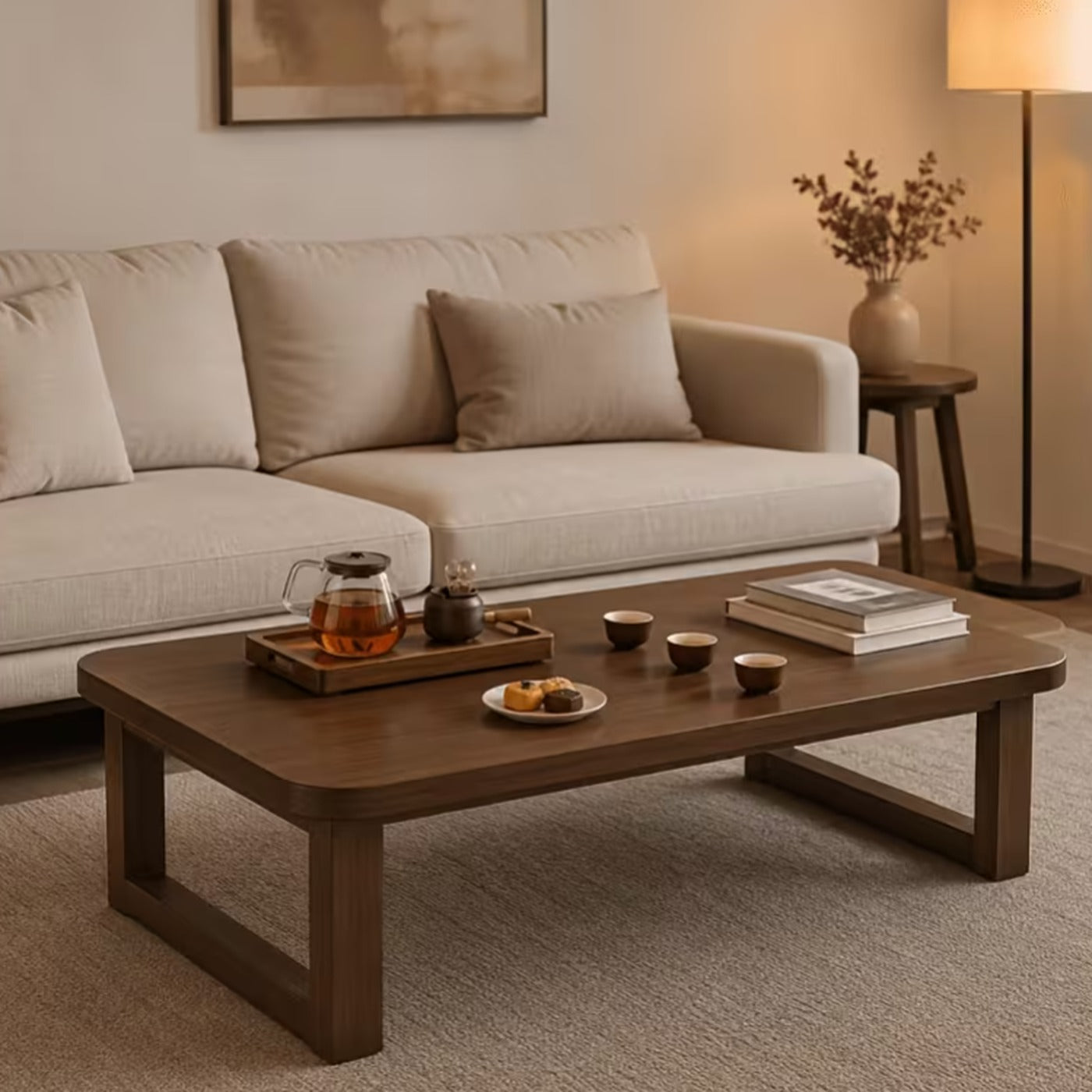 Aveline walnut rounded coffee table in solid wood styled with a tea tray and books in a living room